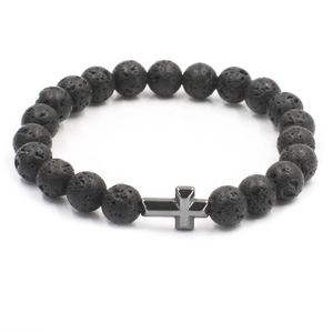 Detailansicht der Lavastein-Struktur und des dunklen Metallkreuz-Anhängers am Armband