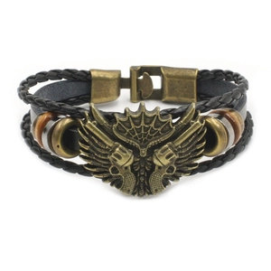 Detail of vintage black braided leather bracelet featuring bronze wing and pistol charms