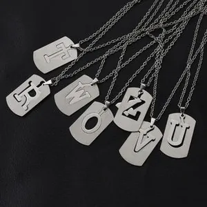 Macro shot of silver hollow letter dog tag necklaces on a black leather surface