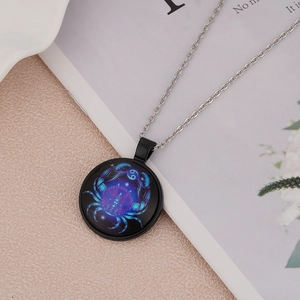 Detail view of a glowing Cancer zodiac pendant on a black chain over a soft pink background