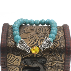 Detail of turquoise beads with silver dragon heads and yellow bead on a vintage wooden box