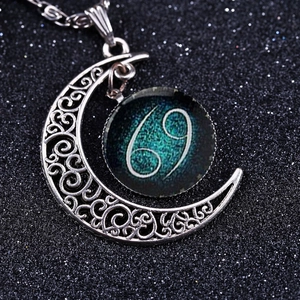 Macro shot of silver crescent moon necklace featuring a Cancer zodiac glowing glass pendant