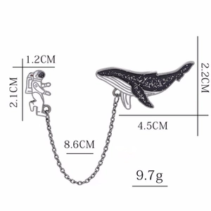 Detail of astronaut and whale enamel pin with chain showing dimensions and weight