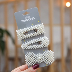 Three-piece set of white faux pearl hair clips with bow and geometric shapes on grey card