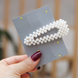 Elegant oval pearl hair clip featuring white imitation pearls on a warm-toned background