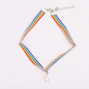 Detailed macro shot of a rainbow-striped choker with a white enamel rabbit pendant detail