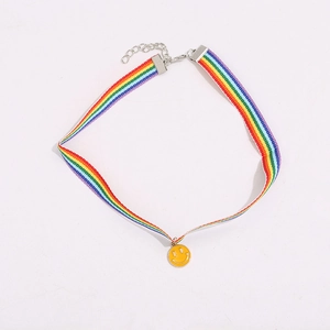 Macro view of rainbow fabric choker featuring a yellow smiley face pendant and metal chain
