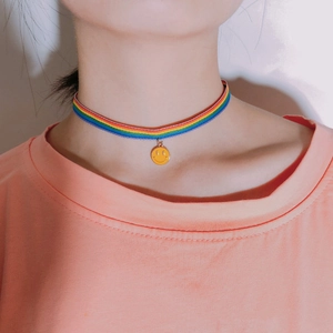 Close-up of rainbow woven choker necklace with a vibrant yellow smiley face pendant