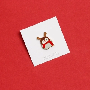 Detail of cute Christmas penguin enamel brooch with reindeer antlers on card