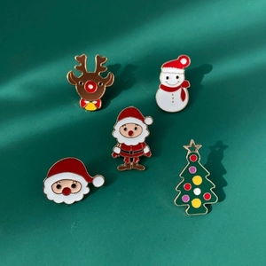 Detailed macro view of five colorful Christmas enamel pins on a dark green surface