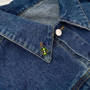 Close-up of a Christmas tree enamel pin on a blue denim jacket collar with metallic star