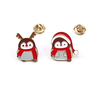 Detail of Christmas penguin enamel pins with festive hats, scarves, and gold metal butterfly clasp