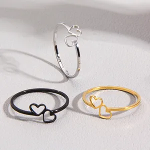 Three minimalist stainless steel rings with hollow double heart design in gold, silver and black