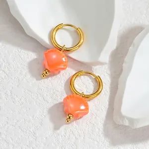 Detailed view of ocean shell tassel earrings in 18K gold and bright orange finish