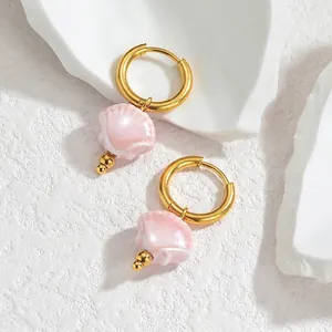 Detailed close-up of pink shell charms on golden titanium earrings with ocean-inspired theme