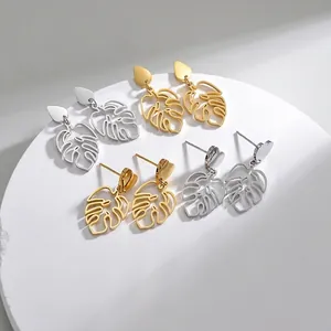 Minimalist hollow monstera leaf earrings in gold and silver finish on white stone base