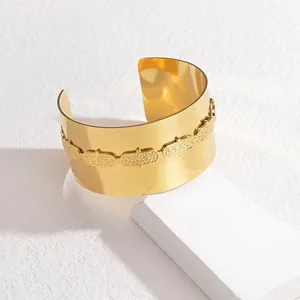Exaggerated wide-face open bangle in 18K gold finish featuring oval embossed textures