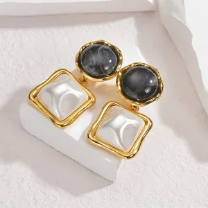 Détail de boucles d'oreilles dorées avec cabochon marbré et accents nacrés de style rétro