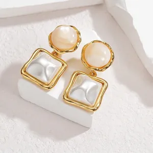 Vue détaillée de boucles d'oreilles perles géométriques dorées sur socle en pierre