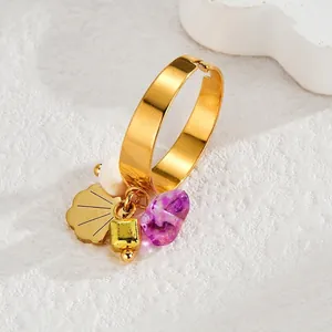 Close-up of golden bohemian ring with purple gemstone, scallop and cube charms
