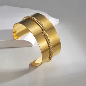 Elegante bracciale rigido aperto largo con finitura dorata e fascia in zirconi pavé