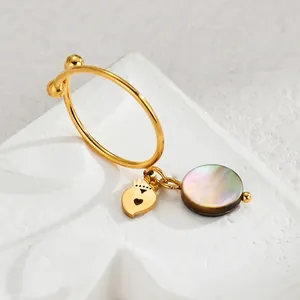 Gold stainless steel ring with heart and mother of pearl charms on a white stone base