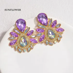 Macro shot of elegant drop earrings featuring purple crystals in a sunburst design