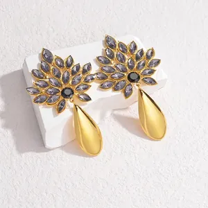 Detail view of 18K gold flower earrings with crystals on a textured stone block