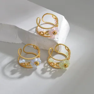 Detail of floral beaded stainless steel rings in gold finish with pastel flower charms