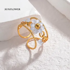 Detail of a gold-tone beaded triple-band ring featuring a light blue flower with seven beads