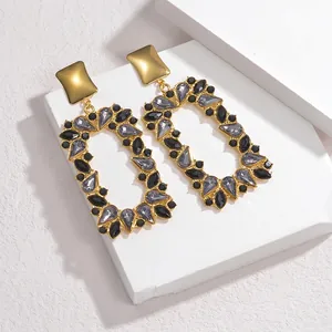 Detailed macro shot of vintage square drop earrings with grey rhinestones and gold plating