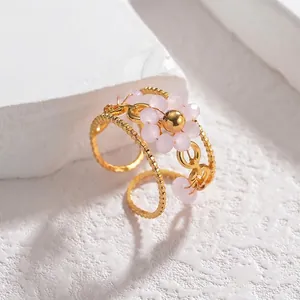 Detailed view of adjustable gold beaded ring with a pink floral bead motif detail