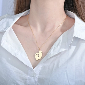 Gros plan du pendentif empreinte de bébé doré sur un collier délicat à maille jasant
