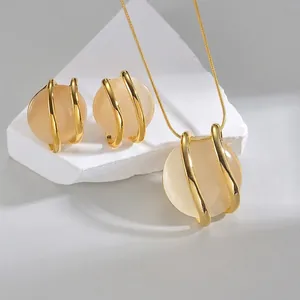 Minimalist gold necklace and earrings set with champagne cat-eye stones on white stone