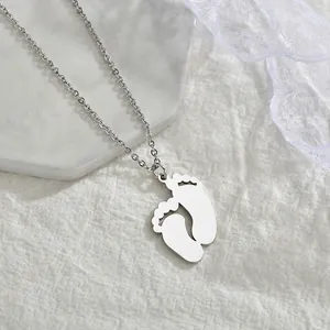 Détail du pendentif pieds de bébé argenté sur marbre pour cadeau personnalisé
