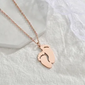 Vue détaillée du pendentif pieds de bébé en or rose sur un plateau de présentation