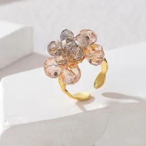 Dettaglio dell'anello a fiore con perline, cristalli champagne e fascia dorata