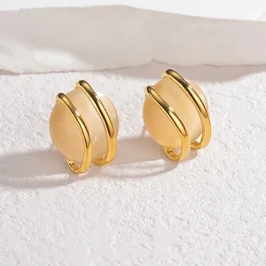 Close-up of golden stud earrings featuring champagne yellow spheres in a circular frame