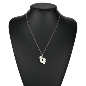 Collier minimaliste en acier inoxydable avec pendentifs pieds de bébé sur support noir