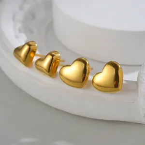 Set of four minimalist golden heart stud earrings with polished mirror finish on white base
