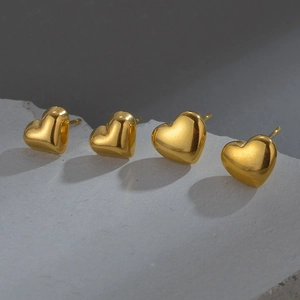 Minimalist gold heart-shaped stainless steel stud earrings set of four on stone background