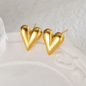 Elegant 18K gold heart stud earrings displayed on a white vintage embossed porcelain plate