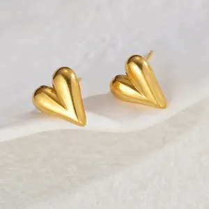 Detailed macro view of 18K gold heart-shaped stud earring on a white ceramic tray