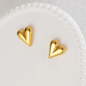Polished 18K gold-plated heart-shaped stud earrings on a white decorative display plate