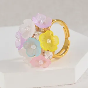 Detailed close-up of a colorful floral ring with a gold adjustable band on a display stand