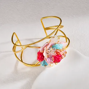 Detail of golden open bangle featuring a colorful 3D enamel flower and crystal core