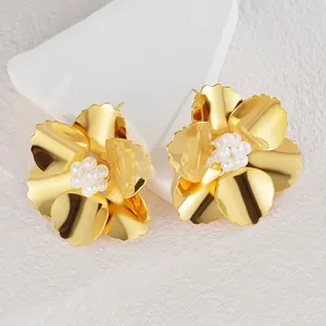 Boucles d'oreilles fleurs dorées avec centre en perles sur présentoir minimaliste