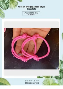 Détail de bracelets de couple tressés roses avec fermoir magnétique et nœuds réglables