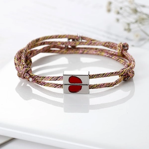 Handwoven couple bracelets with magnetic heart buckle on reflective white base with flowers