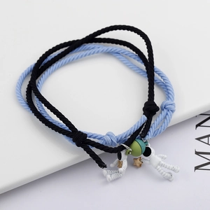 Detail of woven astronaut couple bracelets with star and planet charms in black and blue